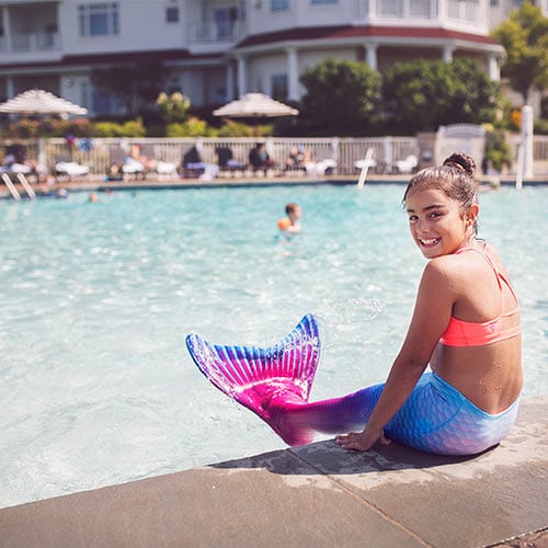 Young girl in mermaid swimsuit by Inn at Bay Harbor pool