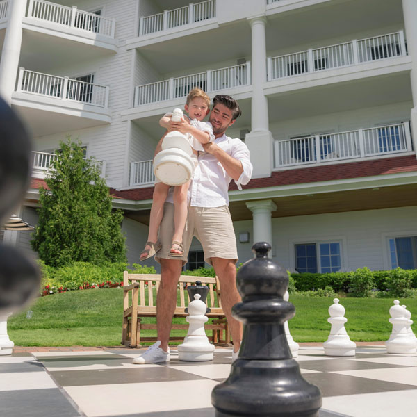 Father, son, playing giant chess lawn games at Inn at Bay Harbor
