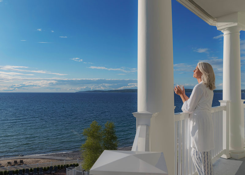 Woman enjoys sunshine with morning coffee on Lake Michigan balcony