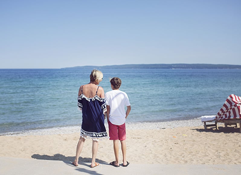 Mom and son embrace on sandy beach, Inn at Bay Harbor