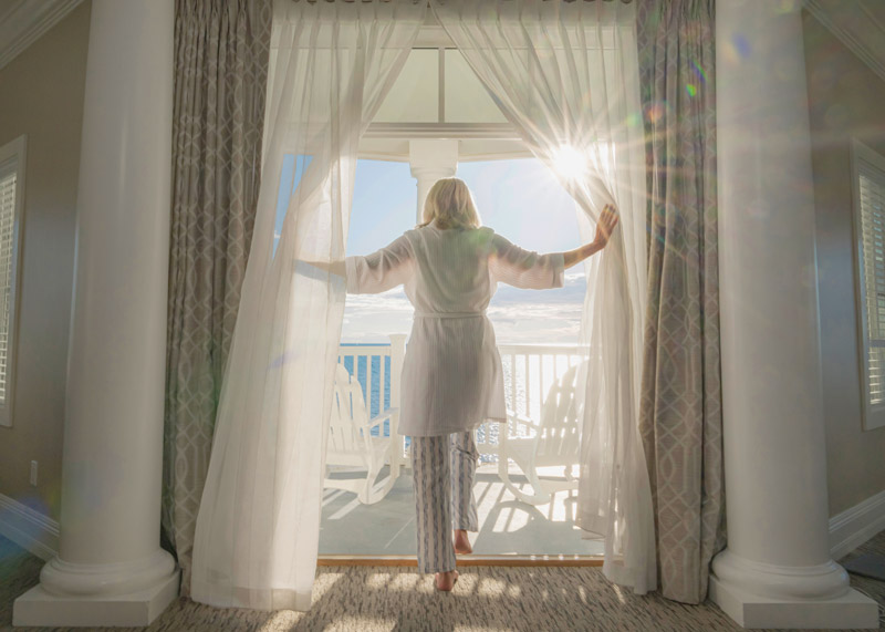Rise & Shine, woman steps onto sunny balcony, Inn at Bay Harbor