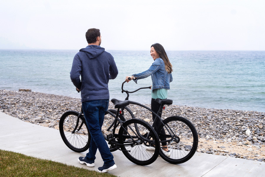 Couple walks black beach cruiser bikes, Lake Michigan
