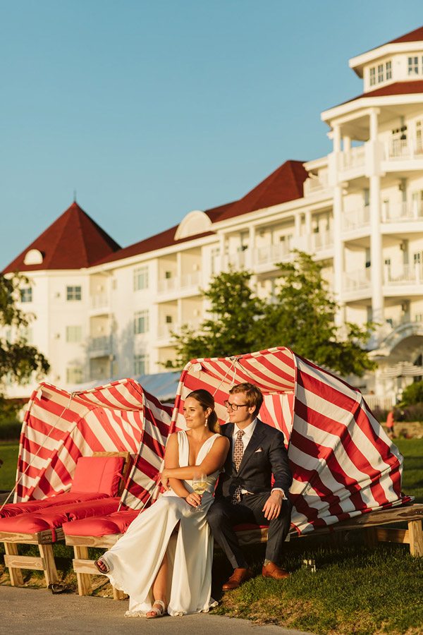 Newlyweds look onto the horizon from signature red beach cabana