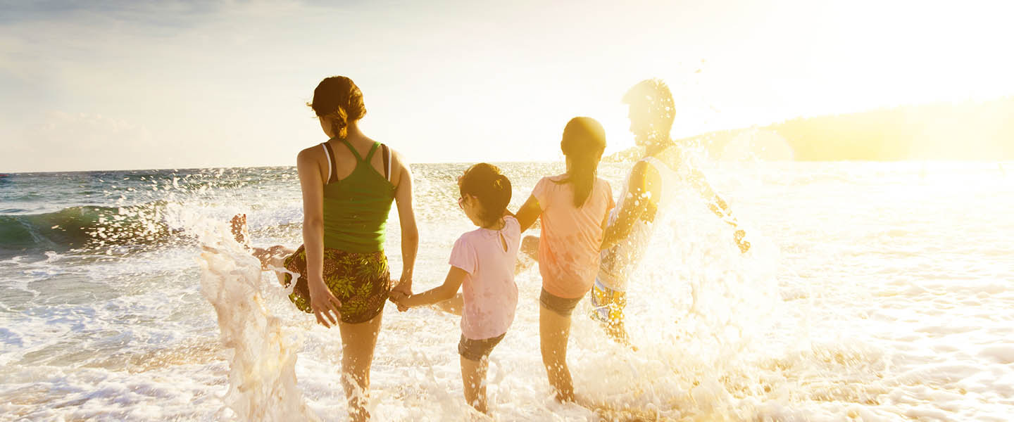 Family splashes in shoreline waves at sunset