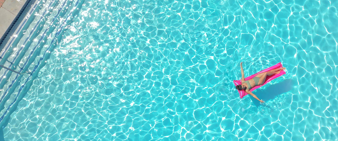 Woman floats in Inn at Bay Harbor's pool on a summer day.